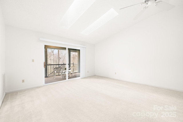 spare room with lofted ceiling with skylight, ceiling fan, baseboards, and light colored carpet