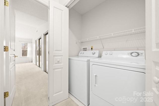 washroom with laundry area, washer and dryer, and light colored carpet