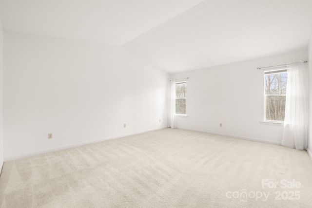 empty room with lofted ceiling, baseboards, and light colored carpet