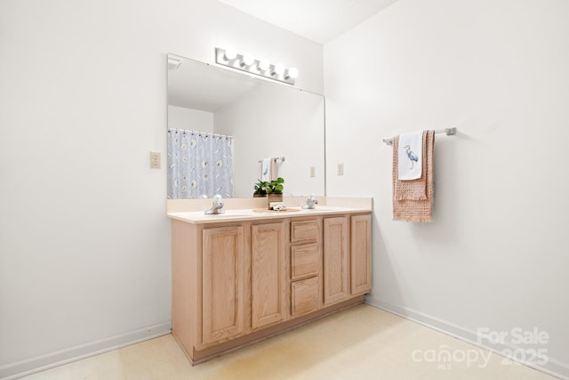 bathroom with double vanity, tile patterned floors, a sink, and baseboards