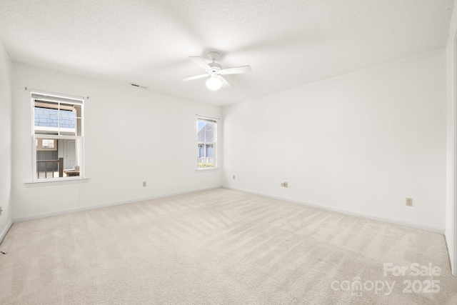 empty room with baseboards, visible vents, ceiling fan, a textured ceiling, and carpet flooring