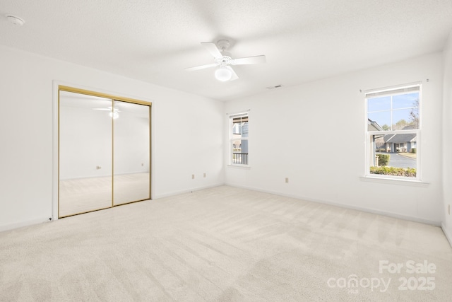 unfurnished bedroom featuring a textured ceiling, carpet floors, a closet, and baseboards