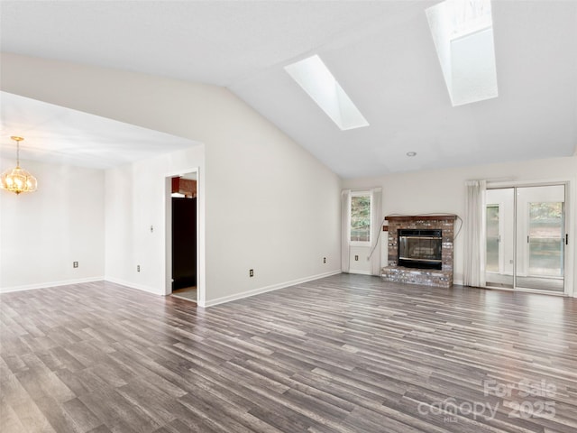 416 Hunters Glen Ln, Hendersonville, NC 28739 - unfurnished living room with a notable chandelier, wood finished floors, vaulted ceiling with skylight, and a fireplace