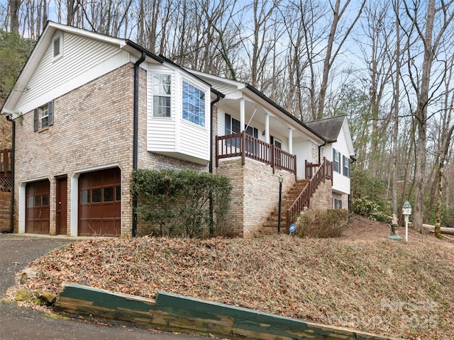 416 Hunters Glen Ln, Hendersonville, NC 28739 - view of property exterior with a garage, aphalt driveway, brick siding, a porch, and stairway