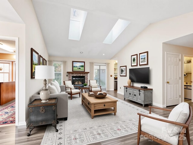 416 Hunters Glen Ln, Hendersonville, NC 28739 - living room with baseboards, a glass covered fireplace, wood finished floors, and vaulted ceiling with skylight
