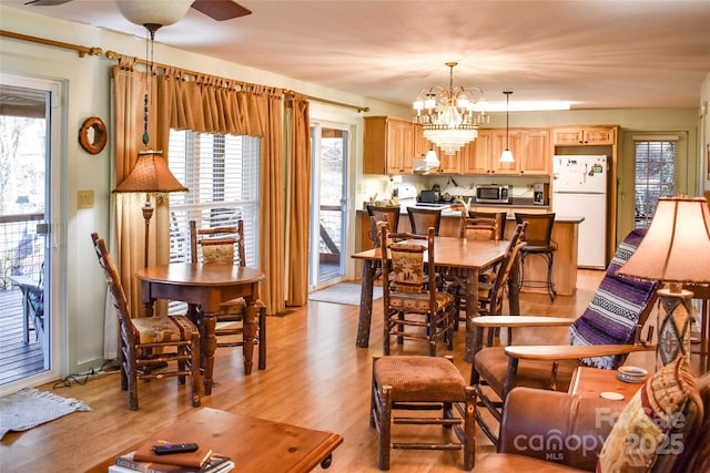 dining area featuring ceiling fan with notable chandelier and light wood-type flooring