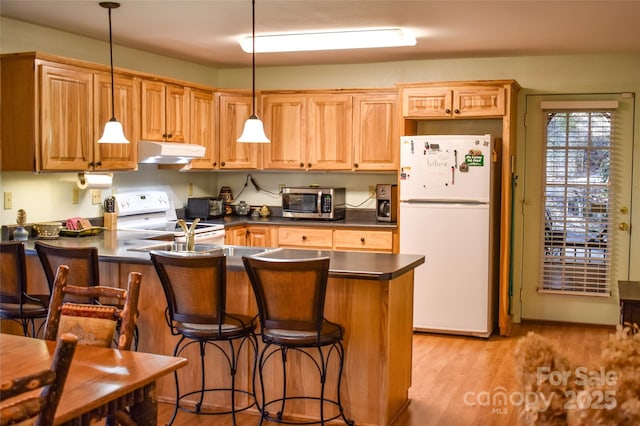 kitchen with light hardwood / wood-style flooring, a kitchen breakfast bar, kitchen peninsula, pendant lighting, and white appliances