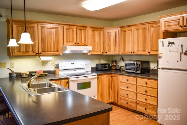 kitchen featuring white appliances, sink, hanging light fixtures, and light wood-type flooring