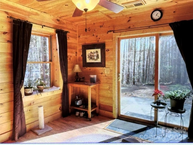 doorway to outside with visible vents, a ceiling fan, wood ceiling, wooden walls, and wood finished floors