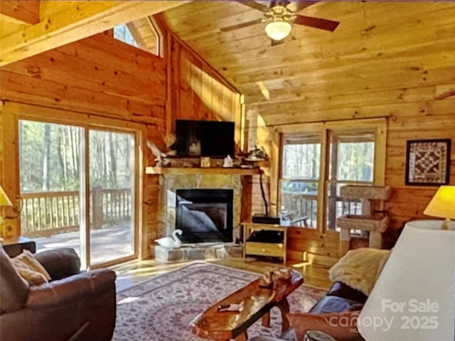 living area featuring a fireplace with raised hearth, wood ceiling, a wealth of natural light, and wooden walls