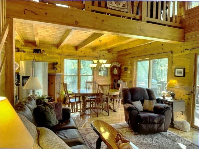 living area featuring a healthy amount of sunlight, an inviting chandelier, beam ceiling, and wooden walls