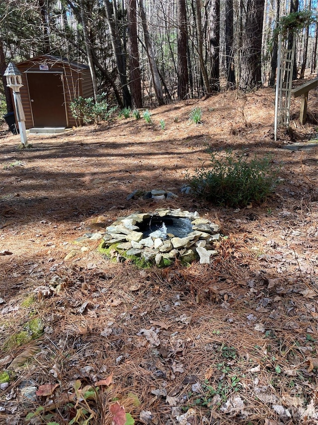 view of yard featuring an outbuilding, a fire pit, and a shed