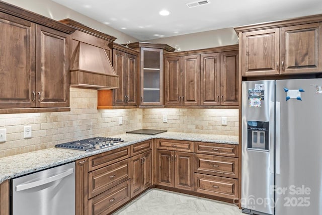 kitchen featuring stainless steel appliances, light stone countertops, and custom range hood