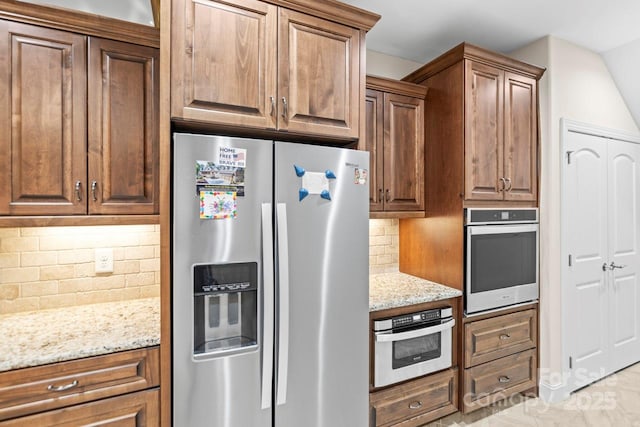 kitchen featuring light stone counters, stainless steel appliances, and decorative backsplash