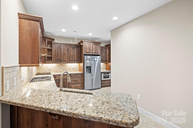 kitchen featuring light stone counters, sink, stainless steel appliances, and kitchen peninsula