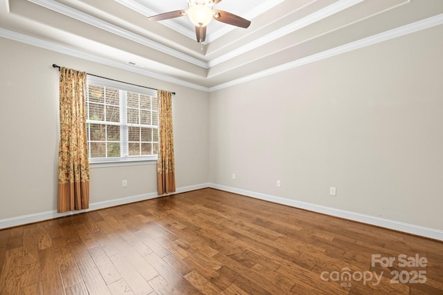 unfurnished room featuring crown molding, ceiling fan, wood-type flooring, and a raised ceiling