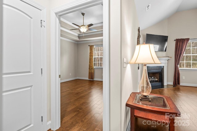 hallway with ornamental molding, dark wood-type flooring, and a tray ceiling