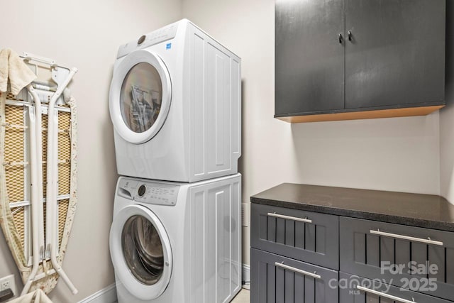 clothes washing area featuring cabinets and stacked washer / dryer