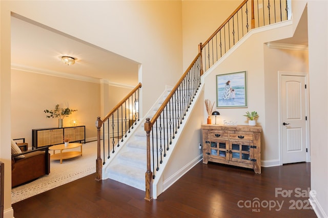 staircase featuring crown molding, wood-type flooring, and a high ceiling