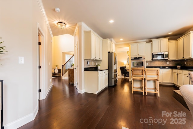 kitchen with a breakfast bar, tasteful backsplash, crown molding, appliances with stainless steel finishes, and dark hardwood / wood-style floors