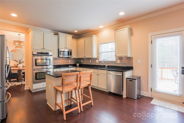 kitchen featuring sink, dark wood-type flooring, stainless steel appliances, a center island, and tasteful backsplash