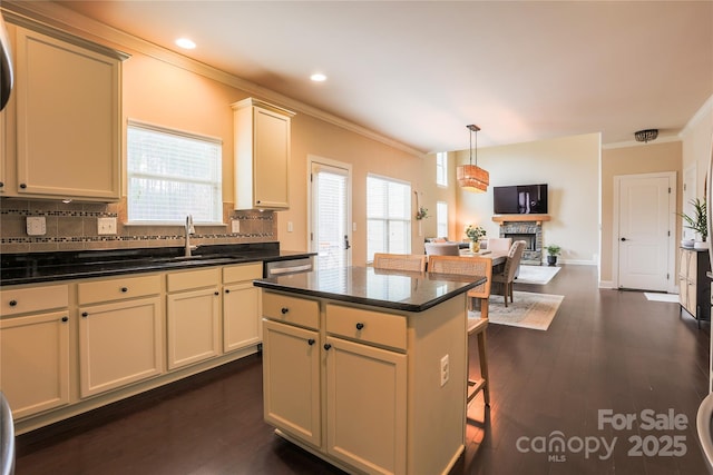 kitchen with pendant lighting, sink, ornamental molding, a kitchen island, and dark hardwood / wood-style flooring