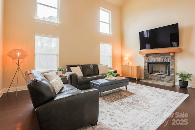 living room featuring a fireplace, a towering ceiling, a wealth of natural light, and dark hardwood / wood-style floors