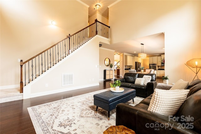 living room featuring crown molding, dark hardwood / wood-style floors, and a towering ceiling