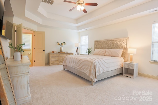 carpeted bedroom featuring a tray ceiling and ceiling fan