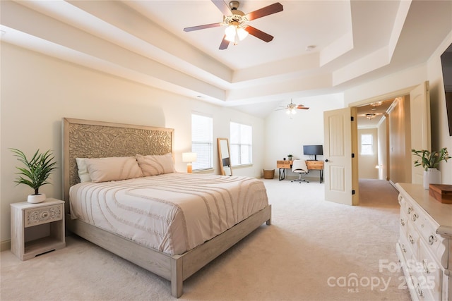 bedroom with ceiling fan, a raised ceiling, and light carpet