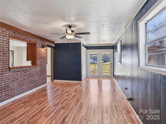 spare room featuring a healthy amount of sunlight, brick wall, and wood finished floors