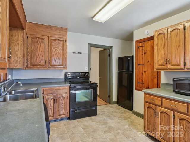 kitchen with brown cabinetry, baseboards, a sink, and black appliances