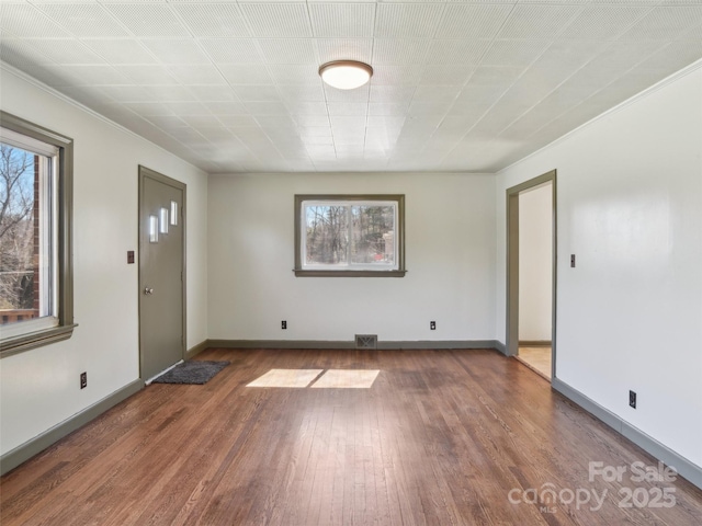 interior space with plenty of natural light, wood finished floors, visible vents, and baseboards