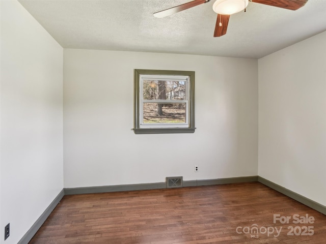 empty room featuring a textured ceiling, wood finished floors, visible vents, and baseboards