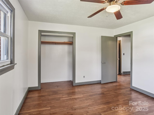 unfurnished bedroom featuring baseboards, a closet, visible vents, and wood finished floors