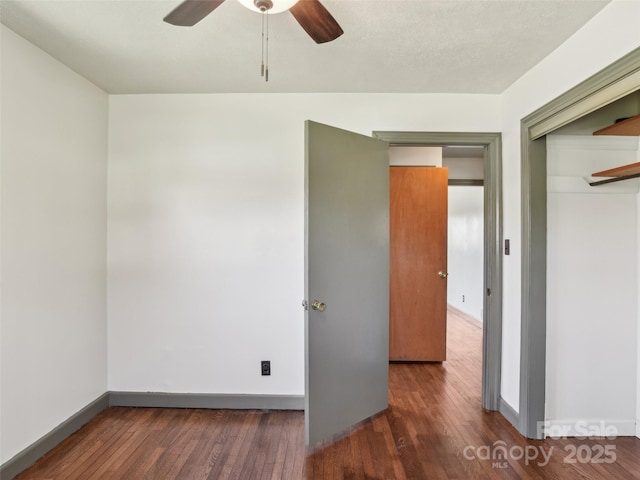 empty room featuring a ceiling fan, baseboards, and hardwood / wood-style floors