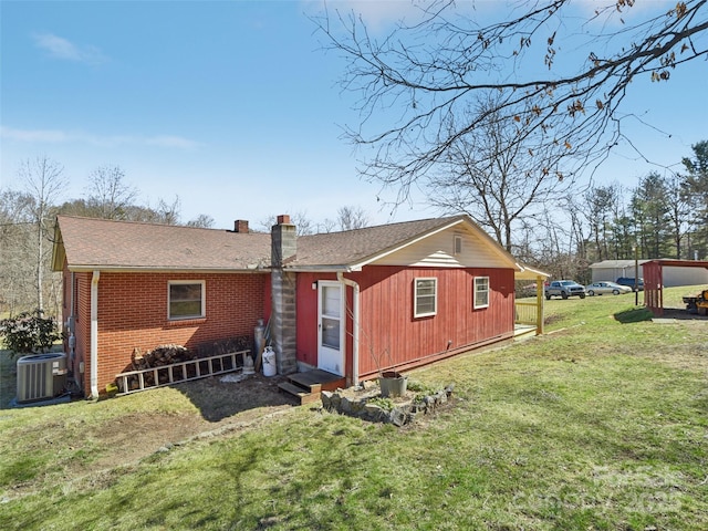 back of house with brick siding, a chimney, a lawn, central AC unit, and entry steps