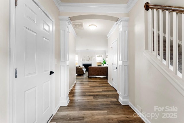 hallway featuring crown molding, dark wood-type flooring, and ornate columns