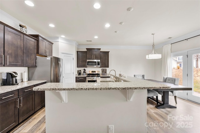 kitchen with appliances with stainless steel finishes, a breakfast bar, sink, and dark brown cabinetry