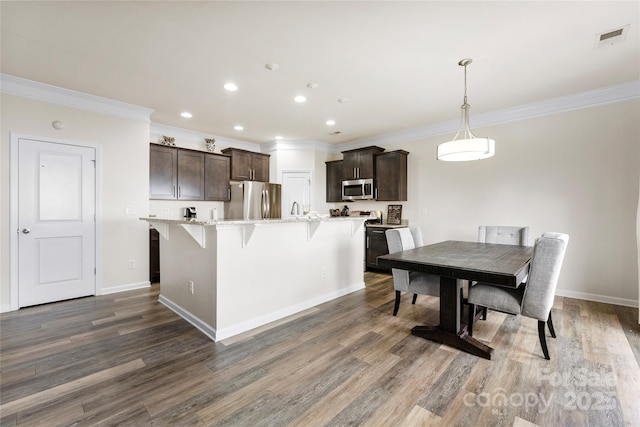 kitchen featuring dark brown cabinetry, decorative light fixtures, stainless steel appliances, and a center island