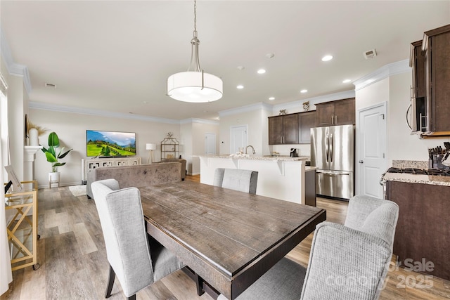 dining room with crown molding and light hardwood / wood-style flooring