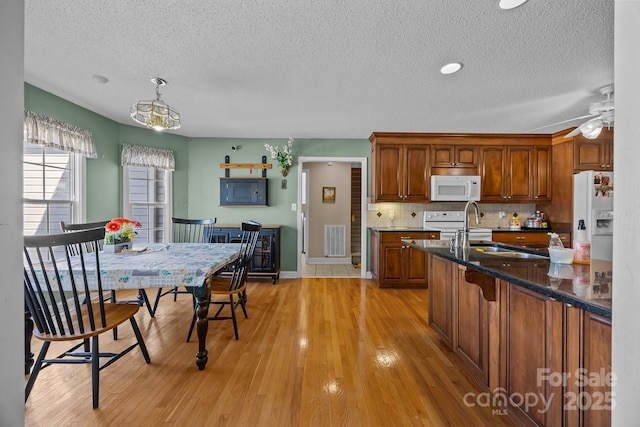 kitchen featuring sink, tasteful backsplash, decorative light fixtures, white appliances, and light hardwood / wood-style floors