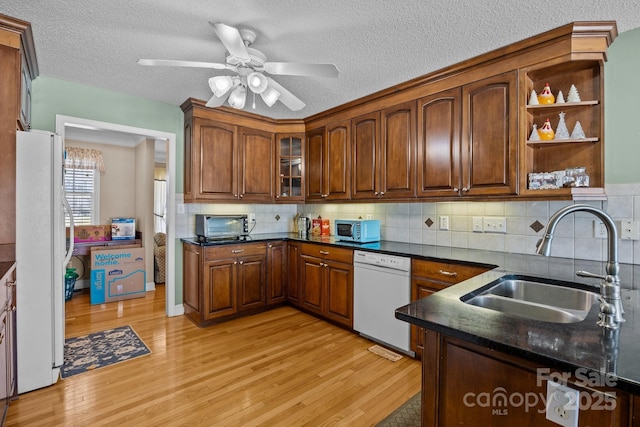 kitchen with backsplash, white appliances, sink, and light wood-type flooring