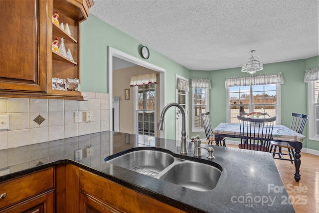 kitchen with pendant lighting, sink, hardwood / wood-style flooring, tasteful backsplash, and a textured ceiling