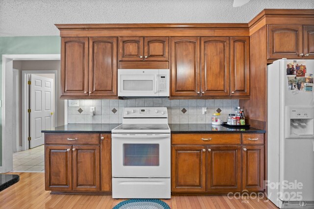 kitchen featuring tasteful backsplash, white appliances, a textured ceiling, and light hardwood / wood-style flooring