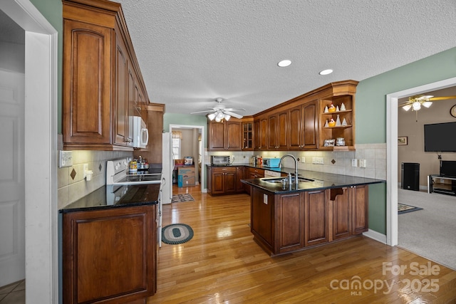 kitchen with ceiling fan, sink, white appliances, and kitchen peninsula