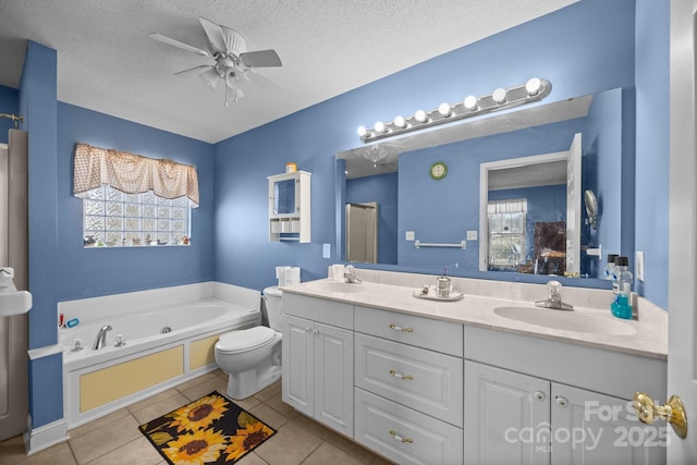 bathroom featuring vanity, tile patterned flooring, a tub, and a textured ceiling