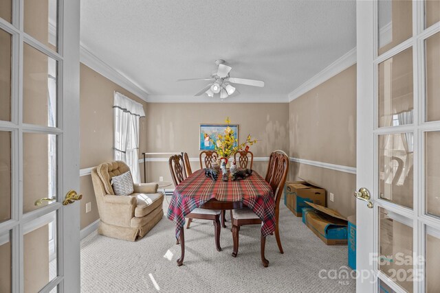 carpeted dining area with ceiling fan, crown molding, french doors, and a textured ceiling