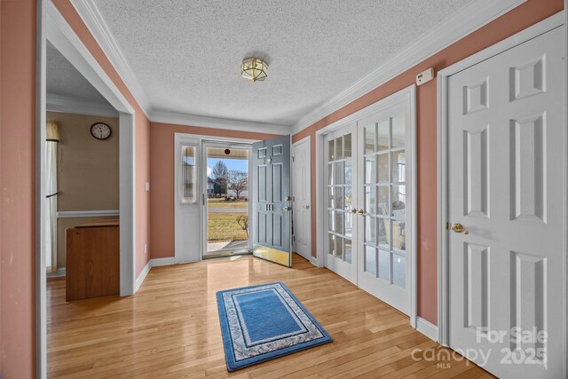 doorway featuring ornamental molding, light hardwood / wood-style floors, a textured ceiling, and french doors