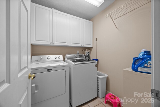 laundry room featuring cabinets, light tile patterned flooring, separate washer and dryer, and a textured ceiling